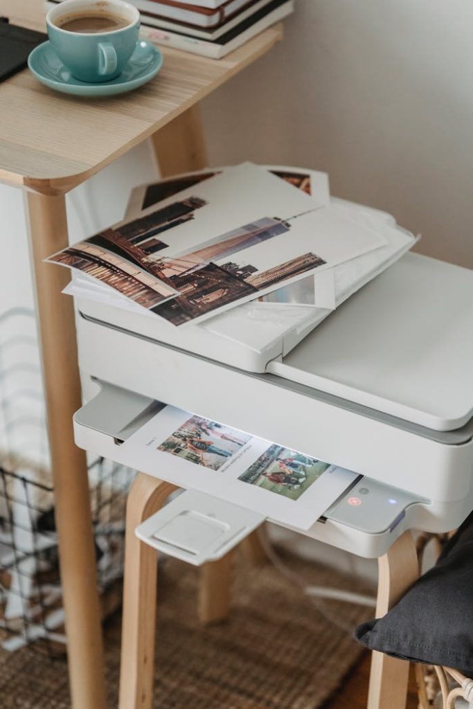 photos-placed-on-printer-near-table-with-cup-of-coffee-7014415 A cozy home office corner with a printer, coffee cup, and printed photos on a wooden table.